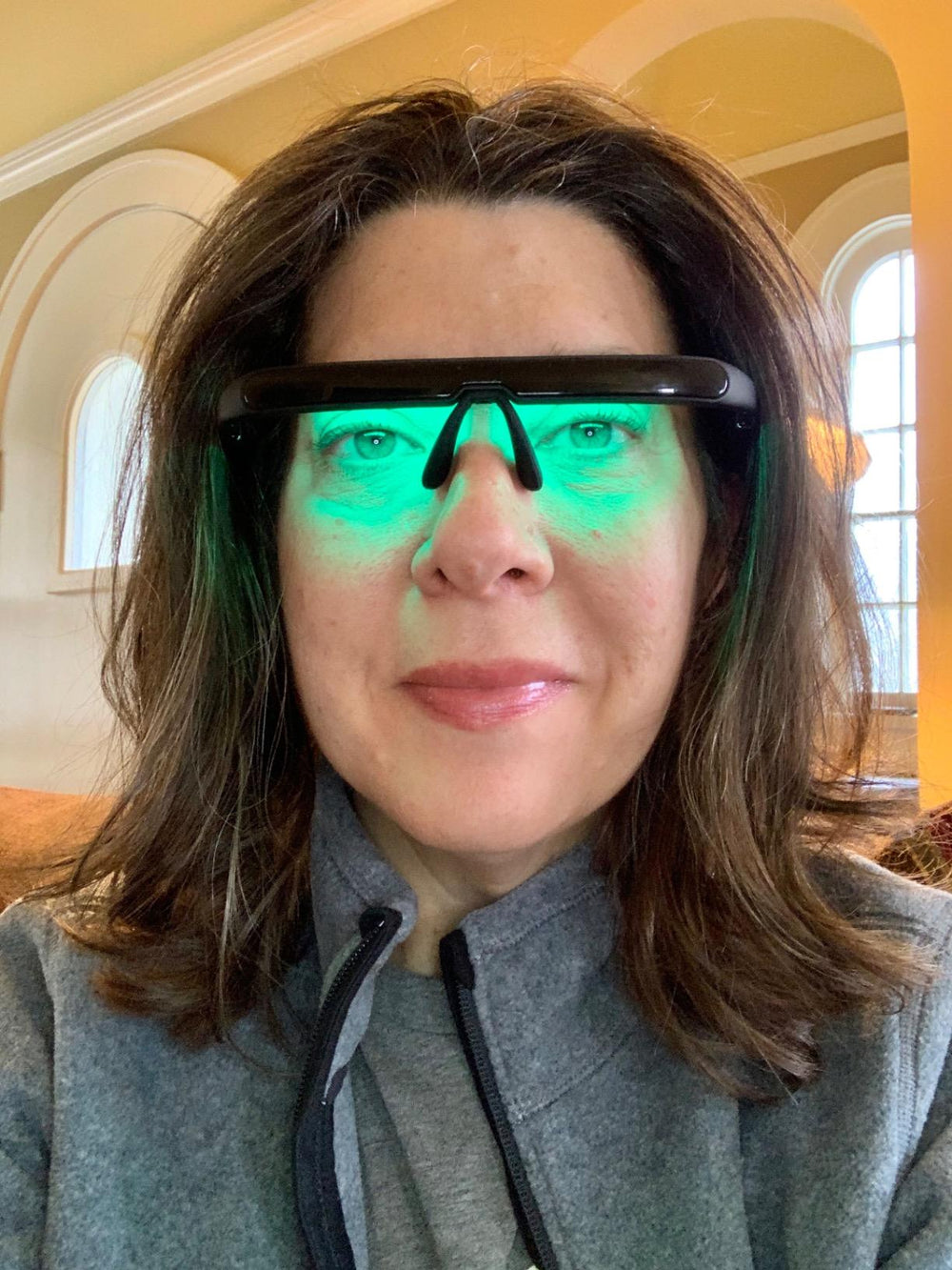 Woman using LUNO Vision green light therapy glasses in a bright interior — natural demonstration of light therapy.